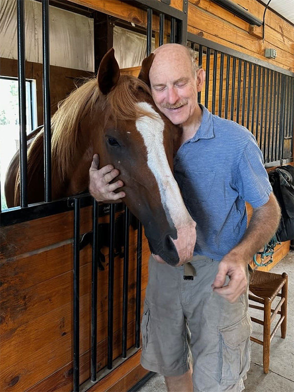 Man petting horse in stable.
