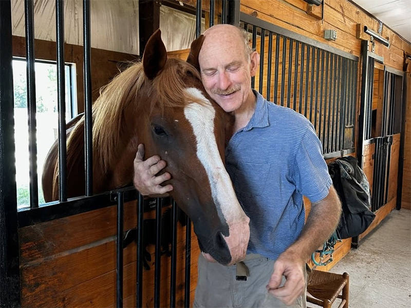Man petting horse in stable.